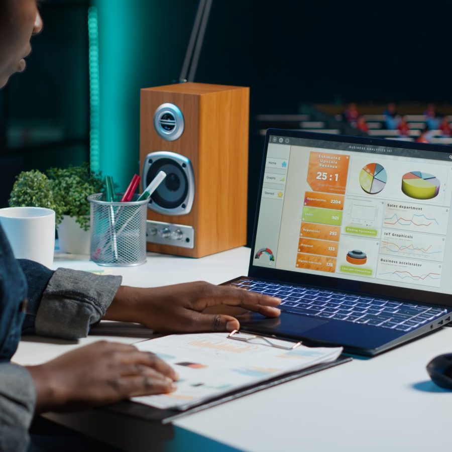 Entrepreneur working from home, using laptop, writing notes on paper. Remote worker in personal apartment office transcribing important info on notepad, looking at statistic charts, camera A